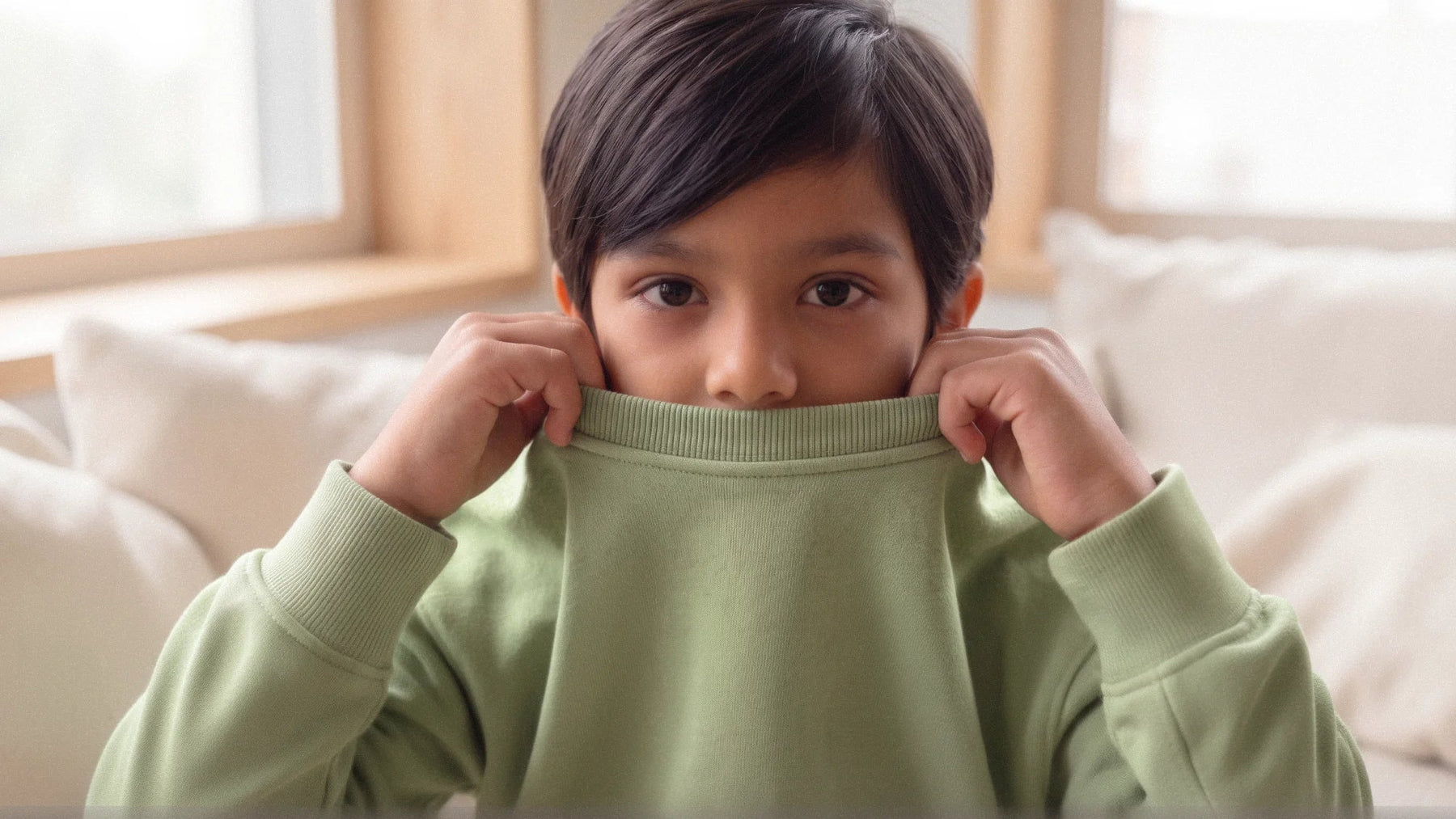 A kid wearing a 100% organic cotton green sweatshirt 