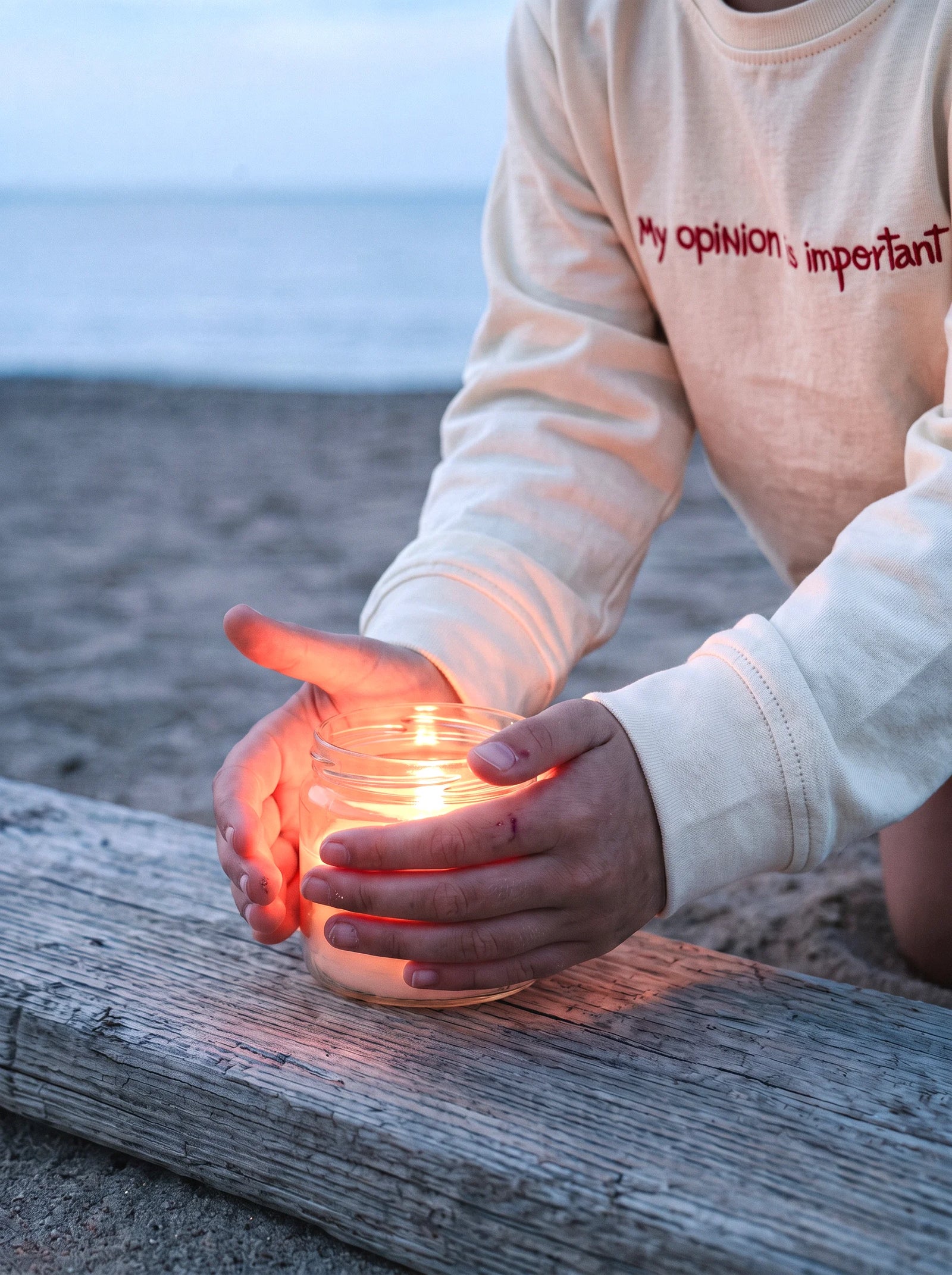 A child's hands cupped around the light of a small flame.