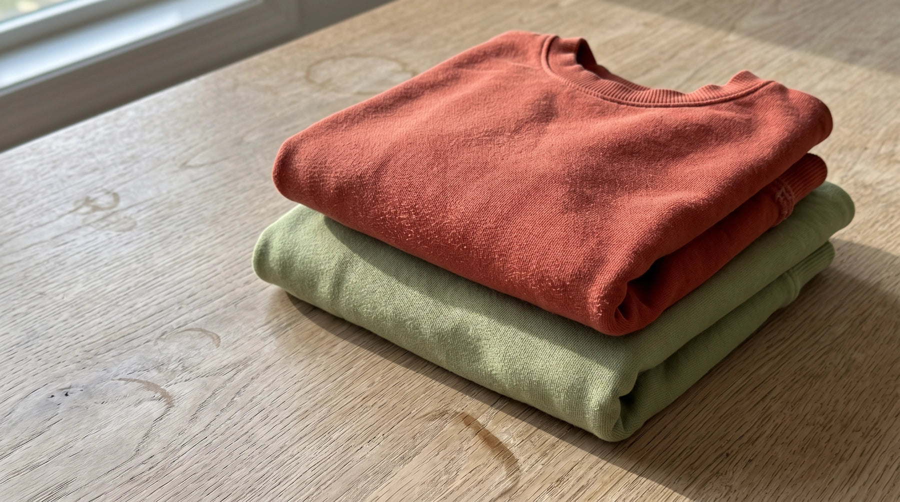 A smaller, well-worn Albor sweatshirt folded on top of a larger one.