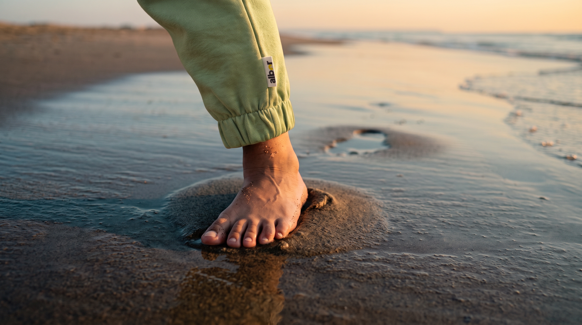 A bare child's foot leaving a print on wet sand.